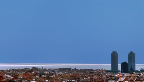 Buildings in city against clear blue sky