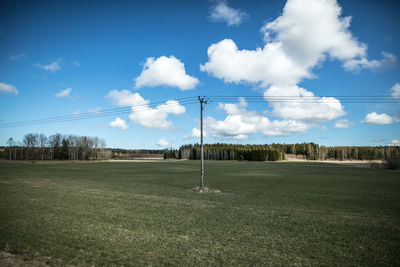 Electricity pylon on grassy field against sky