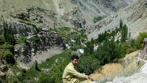 Portrait of young man on rock against mountains pakistani men sitting in the rock 