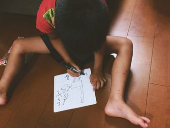 Rear view of a boy sitting on floor at home