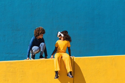 Young couple kissing against yellow wall