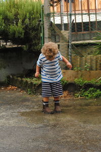 Full length of boy looking down while standing in puddle