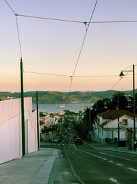 Road by city against sky during sunset