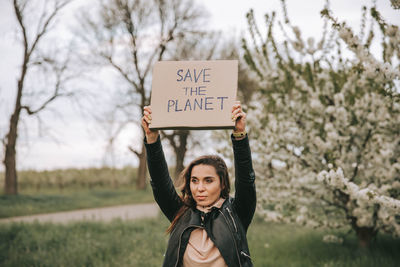Portrait of young woman standing against plants