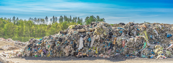 Stack of garbage by plants against blue sky