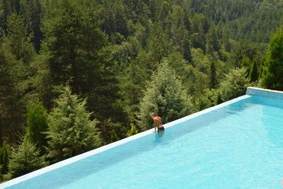 High angle view of young woman standing in swimming pool at forest