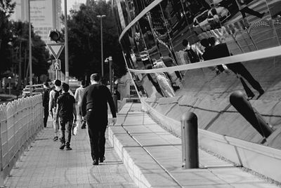 Rear view of men walking on sidewalk in city