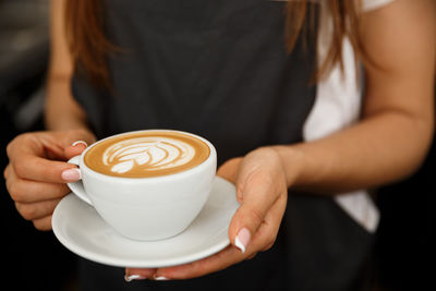 Midsection of woman holding coffee cup