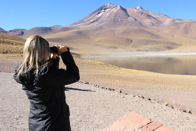 Woman looking through binoculars at desert