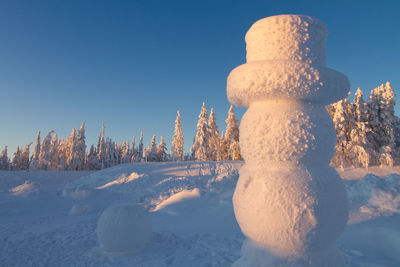 Giant snowman overlooking winter wonderland at sunset