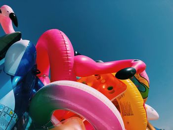 Close-up of various inflatables beach toys on beach against clear summer sky.