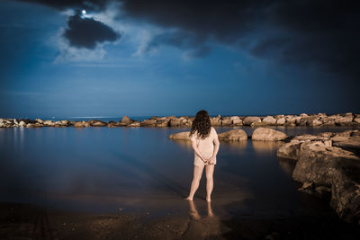 Rear view of woman standing in front of lake