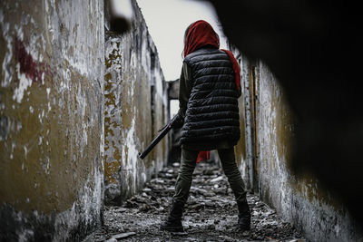 Rear view of woman standing on footpath amidst wall