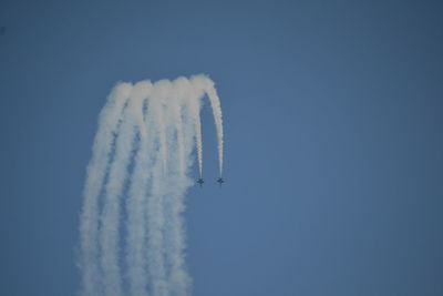 Low angle view of airshow against clear blue sky