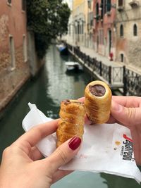 Midsection of woman holding chocolate roll against canal