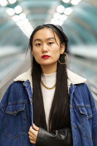 Urban fashion portrait of chinese hipster girl ride escalator to subway. lifestyle and modern trend