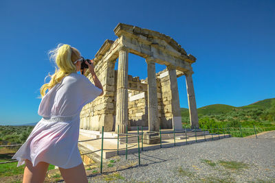 Rear view of woman standing against blue sky