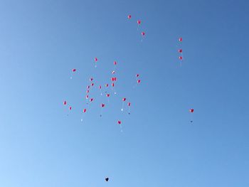 Low angle view of balloons flying against clear blue sky