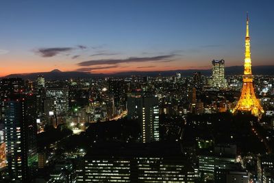 Illuminated tokyo tower in city against sky at dusk