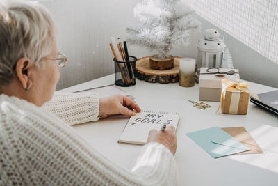 Healthy new years resolutions for older adults. senior mature old woman in white sweater writing