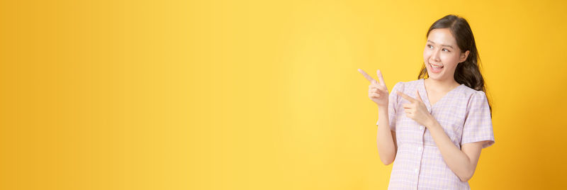 Portrait of a smiling young woman against yellow background