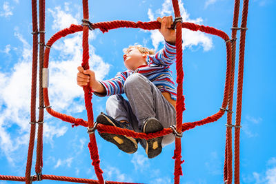 Low angle view of boy climbing on jungle gym