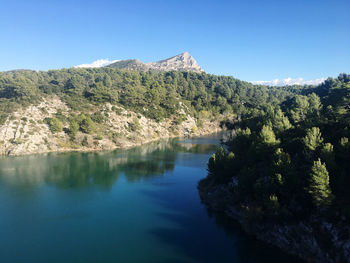 Scenic view of lake and mountains against clear blue sky