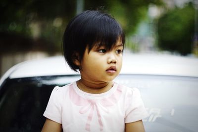 Close-up of cute girl sitting on car