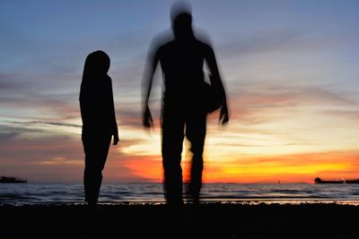 Silhouette man and woman at beach during sunset