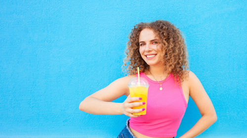 Beautiful woman holds delicious orange juice, cold refreshing summer drink. blue 