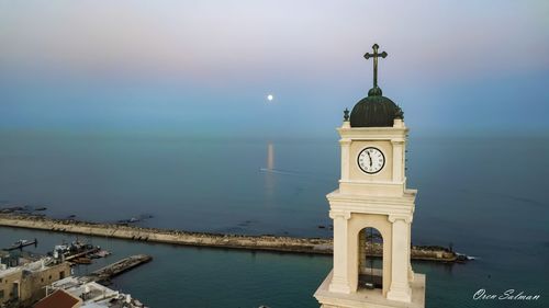 View of lighthouse by building against sky