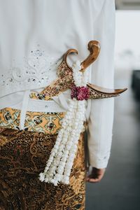 Midsection of person wearing traditional clothing with flowers and sword