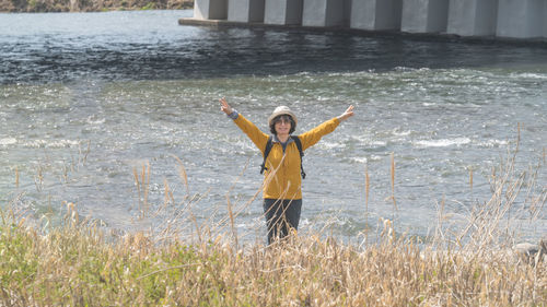 Rear view of woman with arms outstretched standing on field