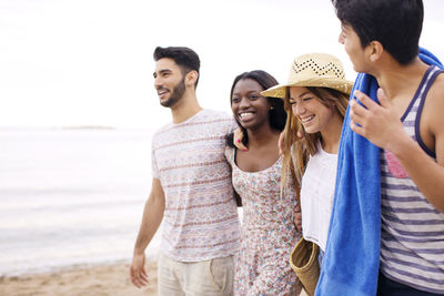 Happy friends walking on beach during vacation