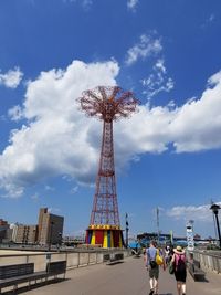 Low angle view of ferris wheel against cloudy sky