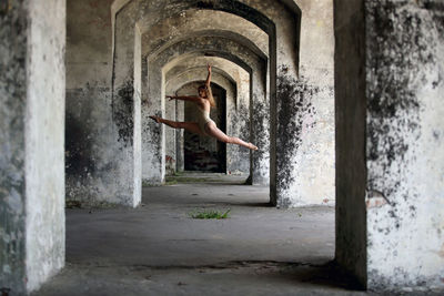 Full length of woman dancing in corridor of abandoned building