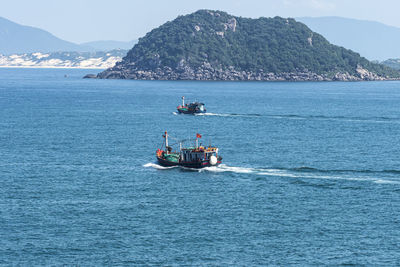 Boat sailing on sea against mountain