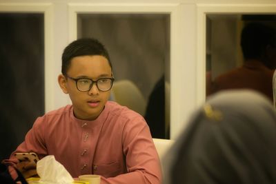 Teenage boy wearing eyeglasses while sitting at restaurant