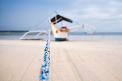 Ship moored on beach against sky