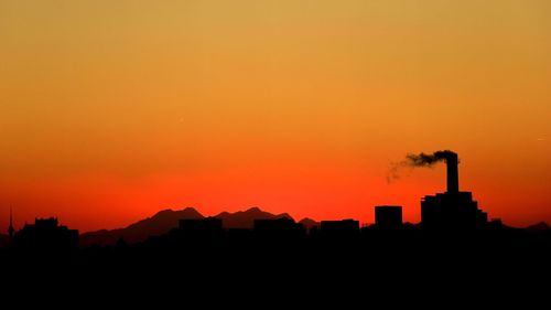 Silhouette of city against orange sky