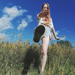 Low angle view of woman standing on field against sky