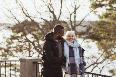 Happy male caregiver and senior woman standing in park