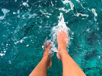 Low section of man splashing water in swimming pool