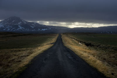 Road amidst field against sky