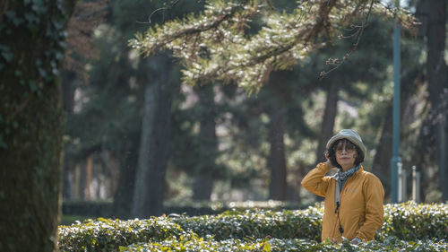 Young woman standing against trees