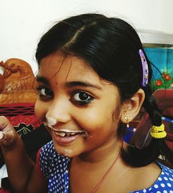Close-up portrait of happy girl with curd on face