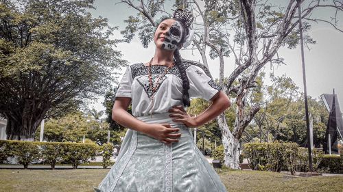 Portrait of young woman standing against trees