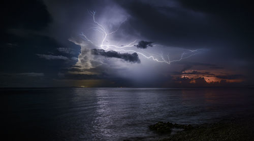 Lightning over sea against dramatic sky