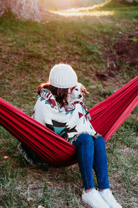 Full length of woman with dog sitting on hammock