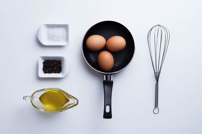 High angle view of saucepan with eggs and spice on white background